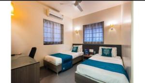 um quarto com 2 camas, uma secretária e um lavatório. em Apollo Guest House em Mumbai