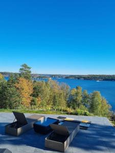 a patio with two tables and a view of a lake at Archipelago villa, cabin & sauna jacuzzi with sea view, 30 minutes from Stockholm in Tyresö