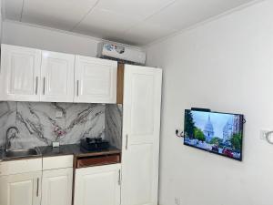 a kitchen with white cabinets and a tv on the wall at Chambre moderne avec cuisine à Bonamoussadi (Kotto) in Douala