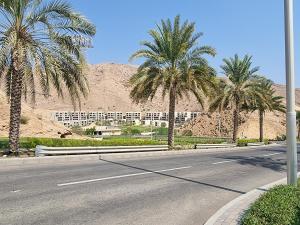 an empty road with palm trees and a building at One Bedroom Apartment Muscat Bay in Muscat