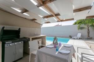 a patio with a table and a kitchen and a pool at Luxury Bungalow in Villaggio Azzurro