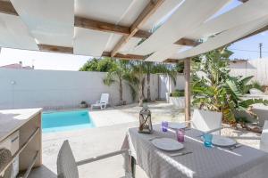 a patio with a table and chairs and a swimming pool at Luxury Bungalow in Villaggio Azzurro