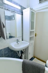 een badkamer met een wastafel, een spiegel en een bad bij Panoráma Apartman in Veszprém