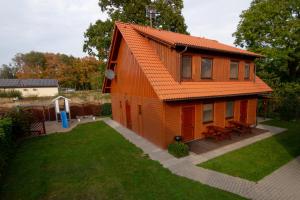 an orange house with an orange roof on a yard at Apartamenty Rodzinne Łukęcin in Łukęcin