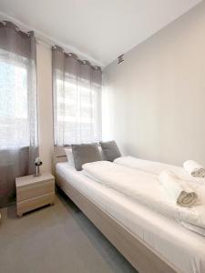a white bedroom with two beds and a window at Keja Aparts - 02 Gdynia Centrum in Gdynia