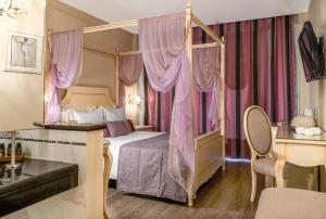 una camera con letto a baldacchino e tende rosa di Danai Hotel & Spa a Olympiakí Aktí