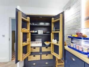 a kitchen with navy blue cabinets and yellow accents at Driftwood Boutique Guest House in Rhosneigr