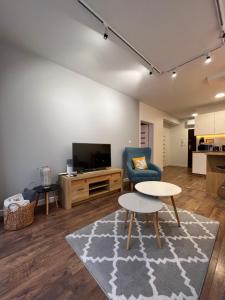 a living room with a tv and a couch and a table at Sosnowe Apartamenty - Marina in Augustów