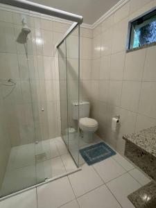 a bathroom with a glass shower with a toilet at Praia da Lagoinha - Mestre Naro in Bombinhas