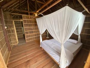 a bed with a canopy in a room with wooden floors at Mambetron Homestay Raja Ampat in Pulau Mansuar