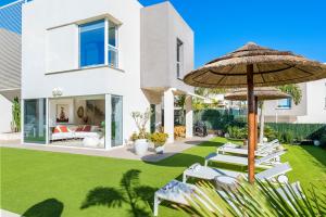 a house with a lawn with chairs and an umbrella at 149 VILLA OASIS Buddha Garden by Sunkeyrents in Adeje