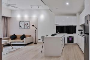 H&N Luxury Suites KLCC في كوالالمبور: غرفة معيشة بيضاء مع أريكة ومطبخ