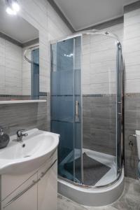 y baño con ducha acristalada y lavamanos. en Keja Aparts - 03 Gdynia Centrum, en Gdynia