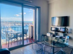 a room with a balcony with a table and a television at ''Luigi'' BALCON SUR LA MER et le Port de Sète in Sète