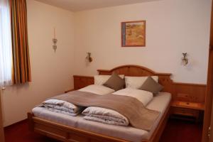 ein Schlafzimmer mit einem Holzbett mit Kissen darauf in der Unterkunft Apart Andrea in Holzgau