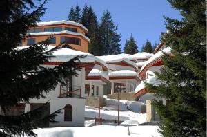 un bâtiment avec de la neige sur le toit dans l'établissement Ski Chalets at Pamporovo - an affordable village holiday for families or groups, à Pamporovo