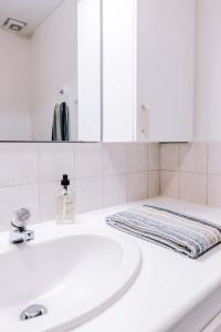 W białej łazience znajduje się umywalka i lustro. w obiekcie Eldá apartments w mieście Mývatn