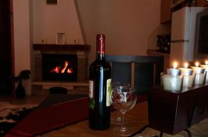 a bottle of wine and a glass on a table with a fireplace at Ski Chalets at Pamporovo - an affordable village holiday for families or groups in Pamporovo