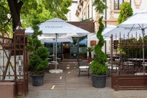 un patio con mesas, sillas y una sombrilla en Hotel Art en Buzau