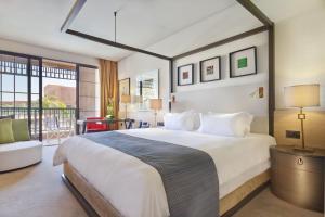 ein Schlafzimmer mit einem großen Bett und einem Balkon in der Unterkunft Hôtel Du Golf Rotana Palmeraie in Marrakesch
