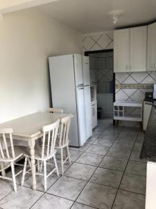 a kitchen with a white refrigerator and a table and chairs at Praia da Lagoinha - Mestre Naro in Bombinhas