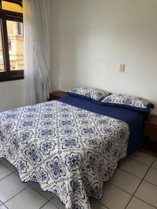 a bedroom with a bed with a blue and white comforter at Praia da Lagoinha - Mestre Naro in Bombinhas