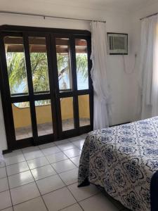 a bedroom with a bed and a glass door at Praia da Lagoinha - Mestre Naro in Bombinhas