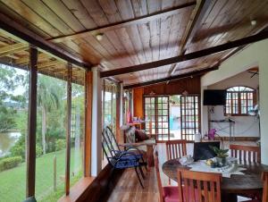 un soggiorno con soffitto in legno, tavolo e sedie. di Recanto Kamei-Piscina climatizada a São Roque
