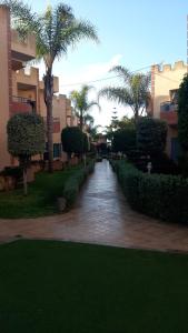 a walkway through a park with palm trees and buildings at Duplex Riad Sidi Bouzid in El Jadida