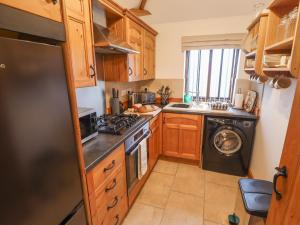 a kitchen with wooden cabinets and a washer and dryer at Tawny Cottage in Alford +20 photos
