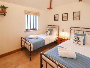 two beds in a room with two windows at Tawny Cottage in Alford