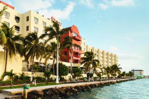 a hotel next to a body of water with palm trees at Ramada by Wyndham Princess Belize City in Belize City