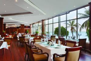 a restaurant with white tables and chairs and windows at Ramada by Wyndham Princess Belize City in Belize City