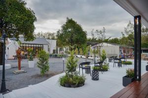 un patio con un mucchio di piante, tavoli e sedie di JB Grand Resort a Nakhon Si Thammarat