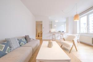 uma sala de estar branca com um sofá e uma mesa em Lumineux Appartement 2 chambres entre le Châtelain et l'Avenue Louise em Bruxelas
