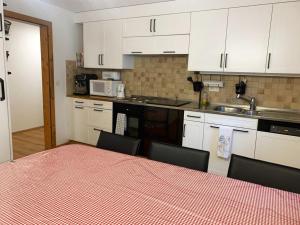 a kitchen with white cabinets and a table with chairs at Privatzimmer Fasser in Müstair- Zentrale Lage in Müstair