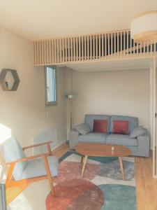 a living room with a couch and a table at Studio proche plage balcon et parking in Deauville