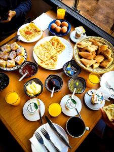 a wooden table with plates of breakfast food on it at Hôtel LAKASBAH Ait Ben Haddou in Aït Ben Haddou