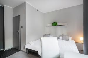 Cette chambre blanche comprend deux lits et un canapé. dans l'établissement Keja Aparts - 04 Gdynia Centrum, à Gdynia