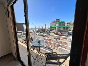 balcón con mesa, sillas y vistas a la ciudad en Spazios Apart Hotel Reñaca, en Viña del Mar