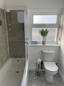 a bathroom with a toilet and a tub and a window at STOP at Talbot Road! in Port Talbot