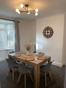 a dining room table with chairs and a clock on the wall at STOP at Talbot Road! in Port Talbot