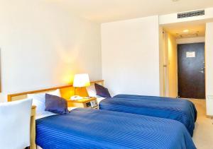 HOTEL LiVEMAX Sapporo Ekimae في سابورو: سريرين في غرفة الفندق ذات شراشف زرقاء