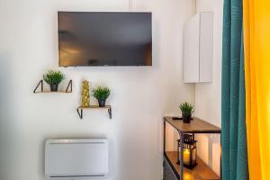 Una sala de estar con un televisor en la pared. en Cocoon - Jardin - Boite à clé - Wi-Fi, en Baulne