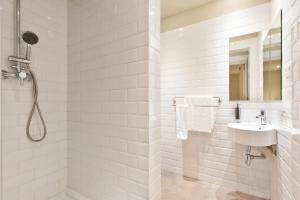 baño blanco con ducha y lavamanos en Ola Living Hostal Diagonal, en Barcelona