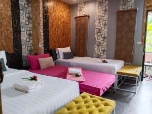 JB Grand Resort في ناخون سي ثامارات: غرفة بها أربعة أسرة مع ملاءات وردية وبيضاء