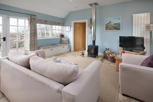 a living room with a white couch and a tv at The Heritage Cottage in Swinton