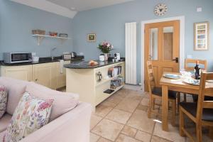 a living room with a couch and a kitchen with a table at The Heritage Cottage in Swinton