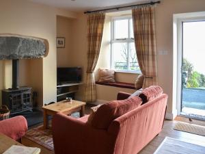 sala de estar con 2 sillas y chimenea en Bluebell Cottage, en Coniston