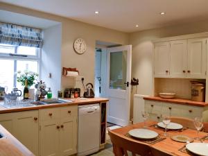 cocina con mesa, fregadero y encimera en Bluebell Cottage, en Coniston